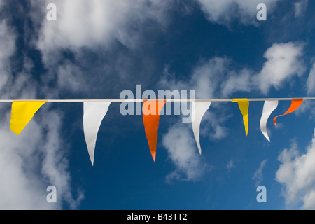 Party Girlanden Fahnen in verschiedenen Farben mit Wolken und blauer Himmel im Hintergrund. Stockfoto