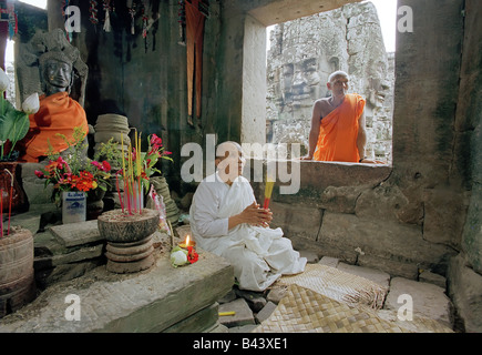 Eine Nonne meditieren neben einer Statue des Buddha in der Bayon-Tempel in Angkor Wat, Siem Reap, Kambodscha, Asien Stockfoto
