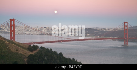 Golden Gate Bridge mit San Francisco und Mond im Hintergrund in der Dämmerung. Stockfoto