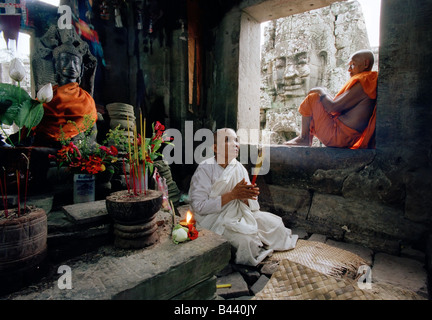 Eine Nonne meditieren neben einer Statue des Buddha in der Bayon-Tempel in Angkor Wat, Siem Reap, Kambodscha, Asien Stockfoto