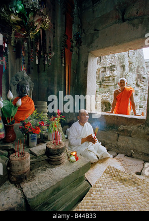 Eine Nonne meditieren neben einer Statue des Buddha in der Bayon-Tempel in Angkor Wat, Siem Reap, Kambodscha, Asien Stockfoto