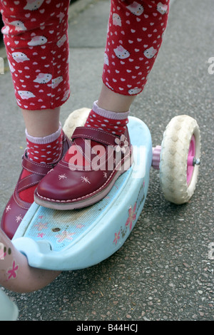 Mädchen mit roten Schuhen auf ihrem Roller Stockfoto