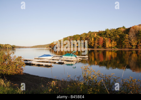 Blick auf einen See mit Boot andockt, umgeben von Herbst Forst- und Laub, Landschaft Stockfoto