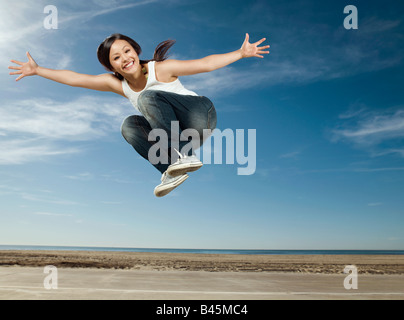Asiatische Frau in die Luft springen Stockfoto