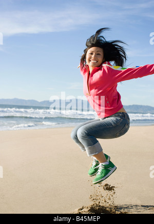Asiatische Frau springen am Strand Stockfoto