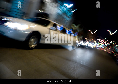 Eine abstrakte Unschärfe einer weißen Limousine in der Stadt in der Nacht mit Lichtspuren Stockfoto