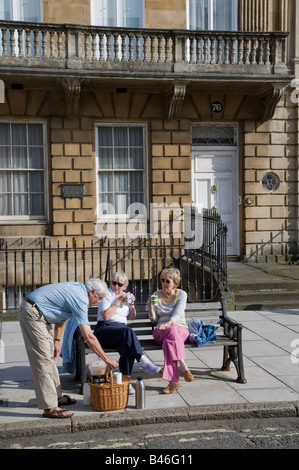 Menschen mit einem Tee-Picknick auf Bank in Straße Bad UK Stockfoto