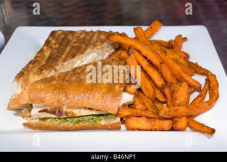 Eine leckere Hähnchen Pesto und Tomate Panini Sandwich mit einer Seitenlänge von Süßkartoffel Pommes frites Stockfoto