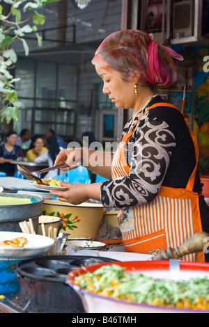 Uyghur Frau Zubereitung von Essen in der Sonntag Marrket in Kashgar in Xinjiang Provinz China Stockfoto