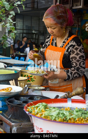 Uyghur Frau Zubereitung von Essen in der Sonntag Marrket in Kashgar in Xinjiang Provinz China Stockfoto