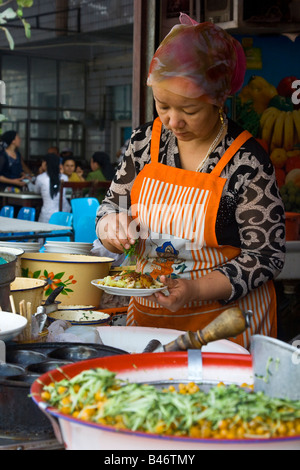 Uyghur Frau Zubereitung von Essen in der Sonntag Marrket in Kashgar in Xinjiang Provinz China Stockfoto