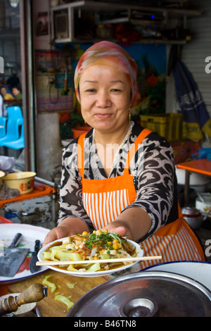 Uyghur Frau Zubereitung von Essen in der Sonntag Marrket in Kashgar in Xinjiang Provinz China Stockfoto