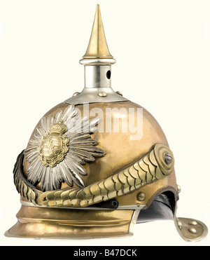 Ein Modell 1875 Helm für eingesessene Männer des Königlich-Sächsischen "Gardereiter-Regiments" (1. Schweres Regiment). Tombac-Schädel mit Nickel-Silber-Trimmung, gerippter Spitze, gekammerte Metall-Chinskalen auf Schraubenrosetten, nationale Kakade rechts. Makers Aufschrift auf der Kantengierung der vorderen Spitze, "Wilh. Jaeger'. Schwarzes Lederfutter. Grüner Lack auf der Innenseite der vorderen Spitze. Einer der Befestigungsstifte der Platte fehlt. Die Kantenleiste am rechten Ohrausschnitt ist ein Ersatz. Nicht reparierter Riss am rechten Ohrausschnitt. Meist unberührter Helm mit Reparaturen aus der Zeit, Stockfoto