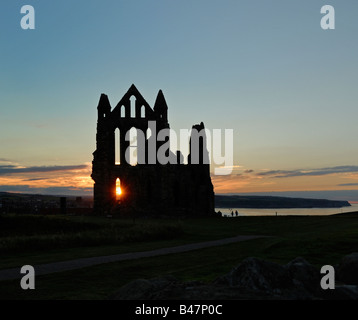 Die untergehende Sonne schimmert durch eine Fensteröffnung in den Ruinen der Benediktinerabtei Kirche in Whitby, North Yorkshire Stockfoto