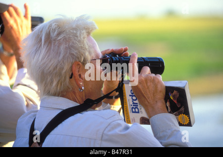 Ältere Frau, die durch ein Fernglas für Vögel beobachten Stockfoto