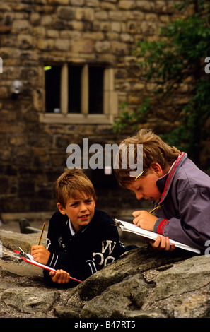 Zwei Jungs machen Zeichnungen af architektonische Details bei einem Schulbesuch in eine historische Stätte. Stockfoto