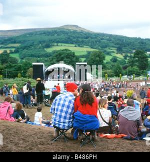 Leute sitzen auf dem schlammigen Hügel beobachten die Bühne auf der Green-Mann-Festival am Glanusk in der Nähe von Abergavenny Wales UK KATHY DEWITT Stockfoto