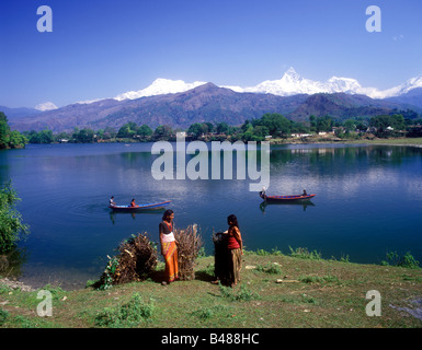 Nepalesische Land Frauen mit großen Bündeln von Brennholz an den Ufern des Sees Phewa Tal von Fishtail Berg übersehen Stockfoto