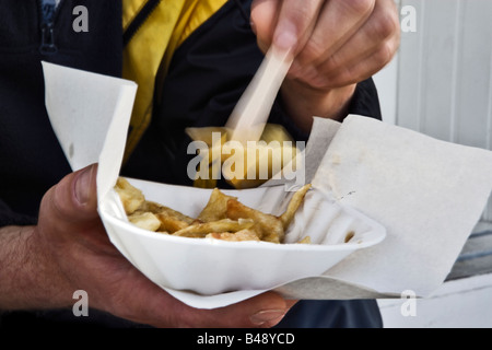 Mann isst Fisch und Chips auf einem Steg am Meer Stockfoto