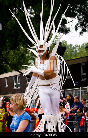 London, Notting Hill Carnival Parade, Mann im weißen Kostüm mit stachelbewehrten Kopf & Finger Tänze auf Stelzen Stockfoto