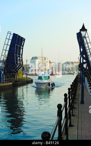 Kleines Fischerboot geht unter einer Brücke in einen Hafen Stockfoto