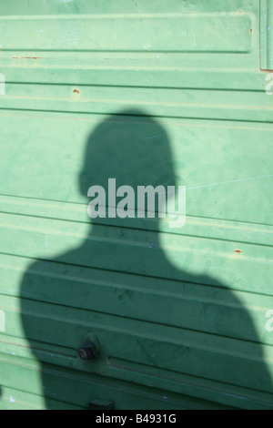 Schatten der Person auf Metallzaun Barriere in Stadt Stockfoto