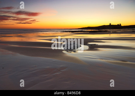 Sonnenaufgang am Embleton Bay mit Dunstanburgh Castle Silhouette am Horizont Northumberland Stockfoto