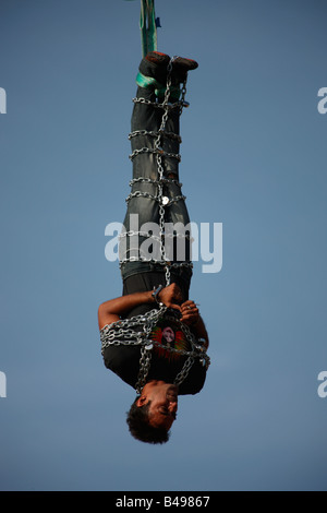 Jadugar Akash angekettet voll hängen in der Luft mit Hilfe eines Krans im Vorspiel zur Feuerleiter Show in Trivandrum, Kerala, Stockfoto