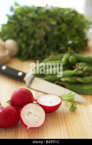 Eine Vielzahl von Gemüse auf einem Holzbrett wie Petersilie Radieschen Bohnen und Pilze Stockfoto