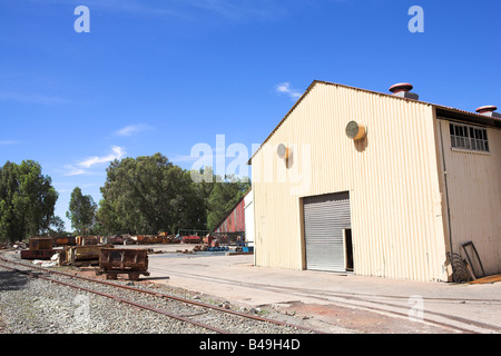 Verrostete Metallbergbau Wagen stehen außerhalb einer Industriehalle Stockfoto