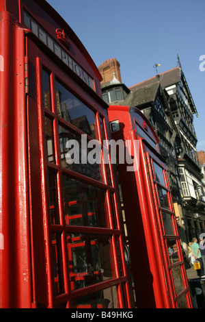 Von Chester, England. Rote Telefonzellen mit Chesters schwarz-weiß Fachwerk Tudor-Stil-Architektur im Hintergrund Stockfoto