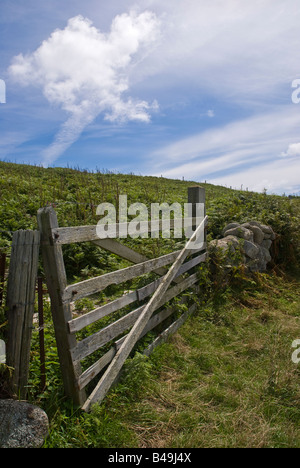 Verwitterte gebrochen sieben-Bar Holztor auf einem sonnigen Hang mit Trockenmauer Stockfoto