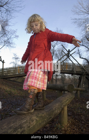 Kleines Mädchen balancing auf einem Baumstamm auf einem Spielplatz, Berlin, Deutschland Stockfoto