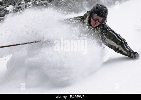 Ein Mann Makinf eine Wende im Tiefschnee mit einem großen Schnee-Spray Stockfoto