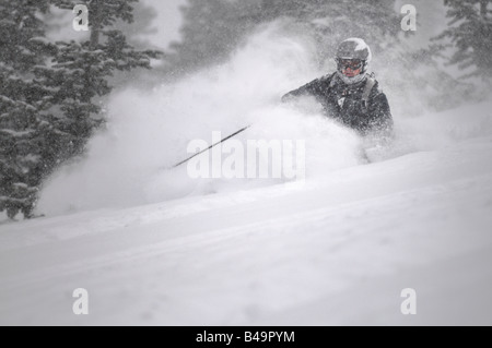 Ein Skifahrer im Tiefschnee mit einem großen Spray Schnee während eines Schneesturms Stockfoto