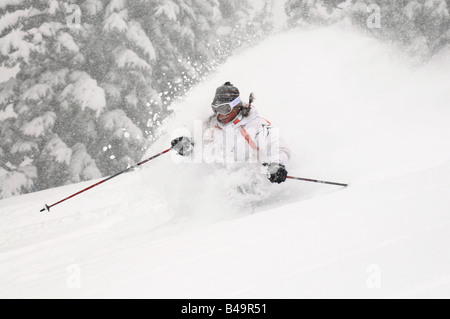 Eine Frau, die Ski im Tiefschnee während eines Sturms mit einem großen Schnee-spray Stockfoto