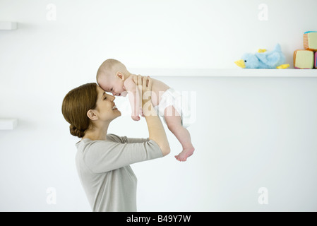 Mutter Baby in die Luft heben berühren Stirn, Seitenansicht Stockfoto