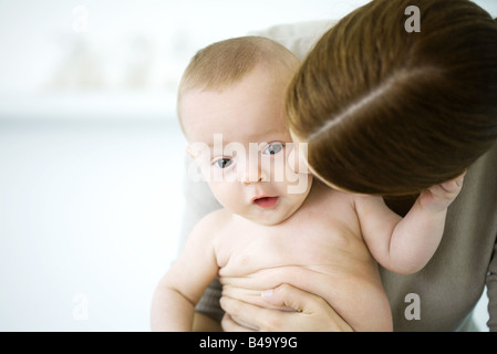 Frau küsst die Wange des Babys, Baby Blick in die Kamera Stockfoto