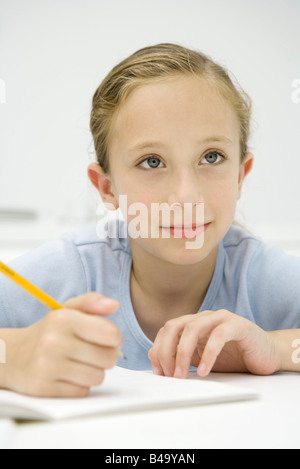 Mädchen sitzen am Tisch, schreiben in Notebook, wegschauen Stockfoto