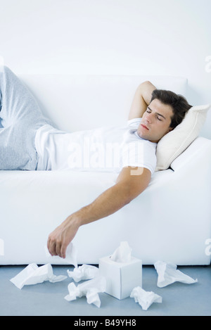 Mann auf Sofa, ausrangierte Gewebe auf dem Boden neben ihm liegend Stockfoto