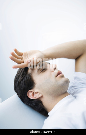 Mann liegend mit geschlossenen Augen, Hand auf Stirn Stockfoto