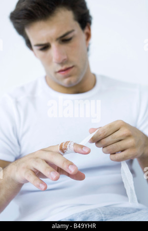 Mann, die Gaze um verletzten Finger wickeln Stockfoto