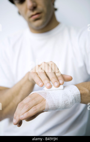 Mann, die Umhüllung Gaze um sein Handgelenk und Hand, verkürzte Ansicht Stockfoto