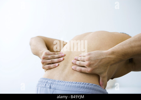 Mann beugte sich über, beschnitten Ansicht hält zurück, niedriger Stockfoto