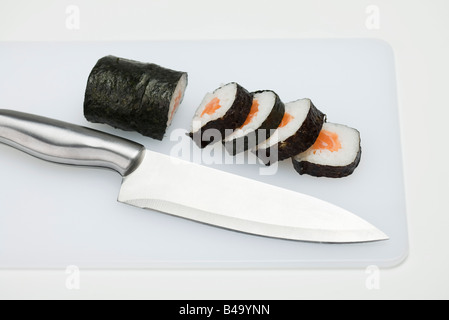 Teilweise geschnittenen Rollen der Maki-Sushi auf Schneidebrett mit Messer Stockfoto