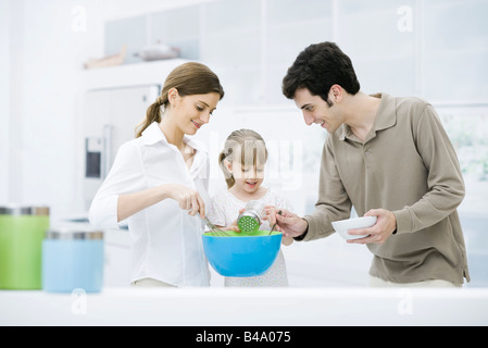 Kleines Mädchen helfen Eltern in der Küche kochen Stockfoto