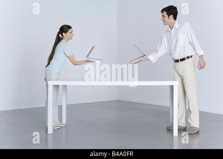 Mann und Frau an den entgegengesetzten Enden des Tisches, mit Laptop-Computer in einer anderen Richtung Stockfoto