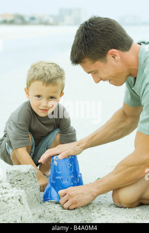 Mann, der eine Sandburg mit jungen Sohn Stockfoto