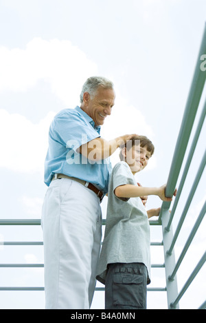 Ältere Mann mit Enkel auf Balkon, seine Hand auf seinem Kopf, beide Lächeln Stockfoto