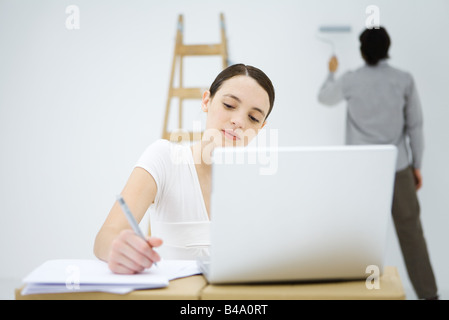 Junge Frau mit Laptop-Computer, der Mensch in Malerei Hintergrundwand Stockfoto